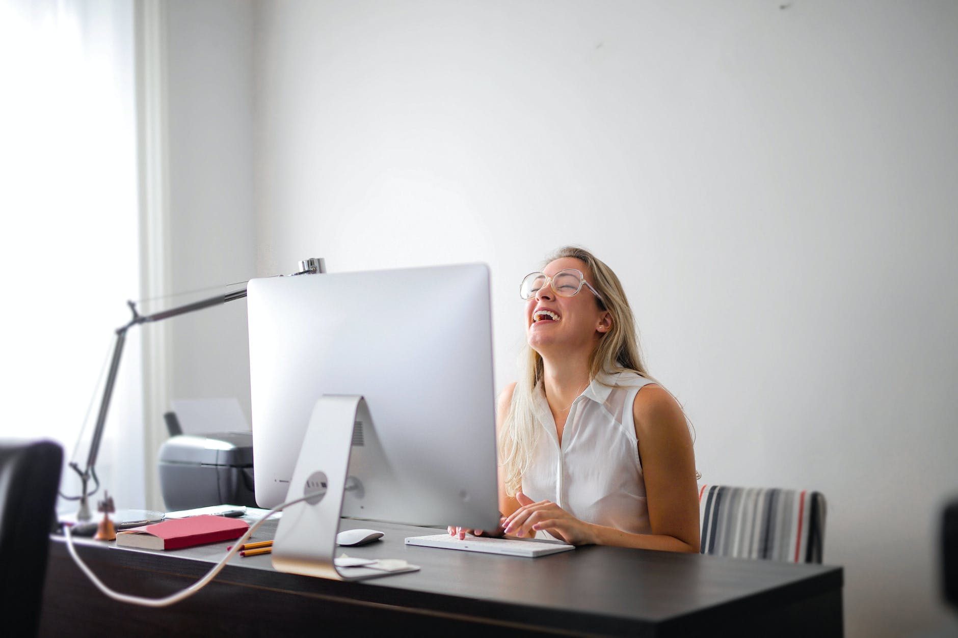 woman in white tank top using macbook air on brown wooden table