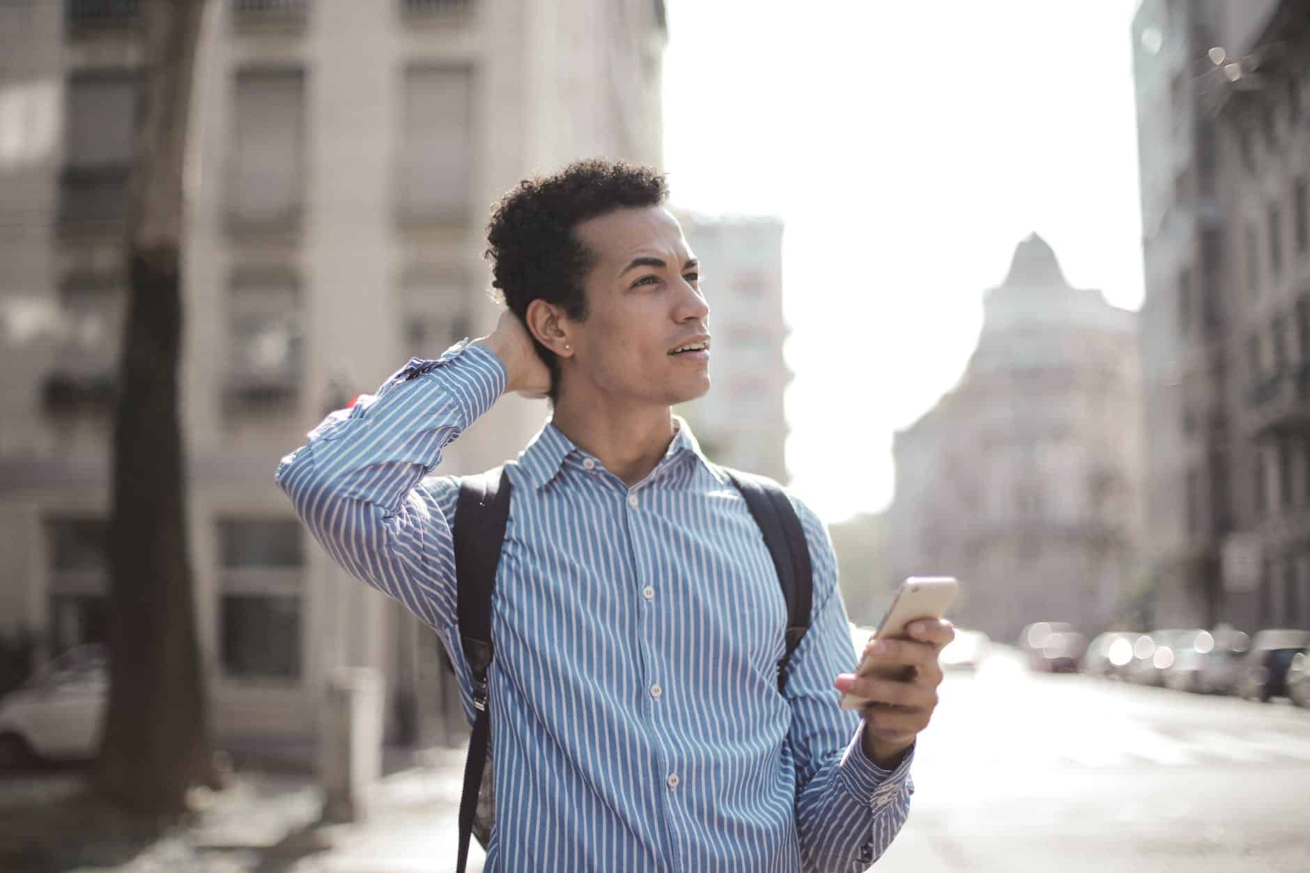 thoughtful man using smartphone on street